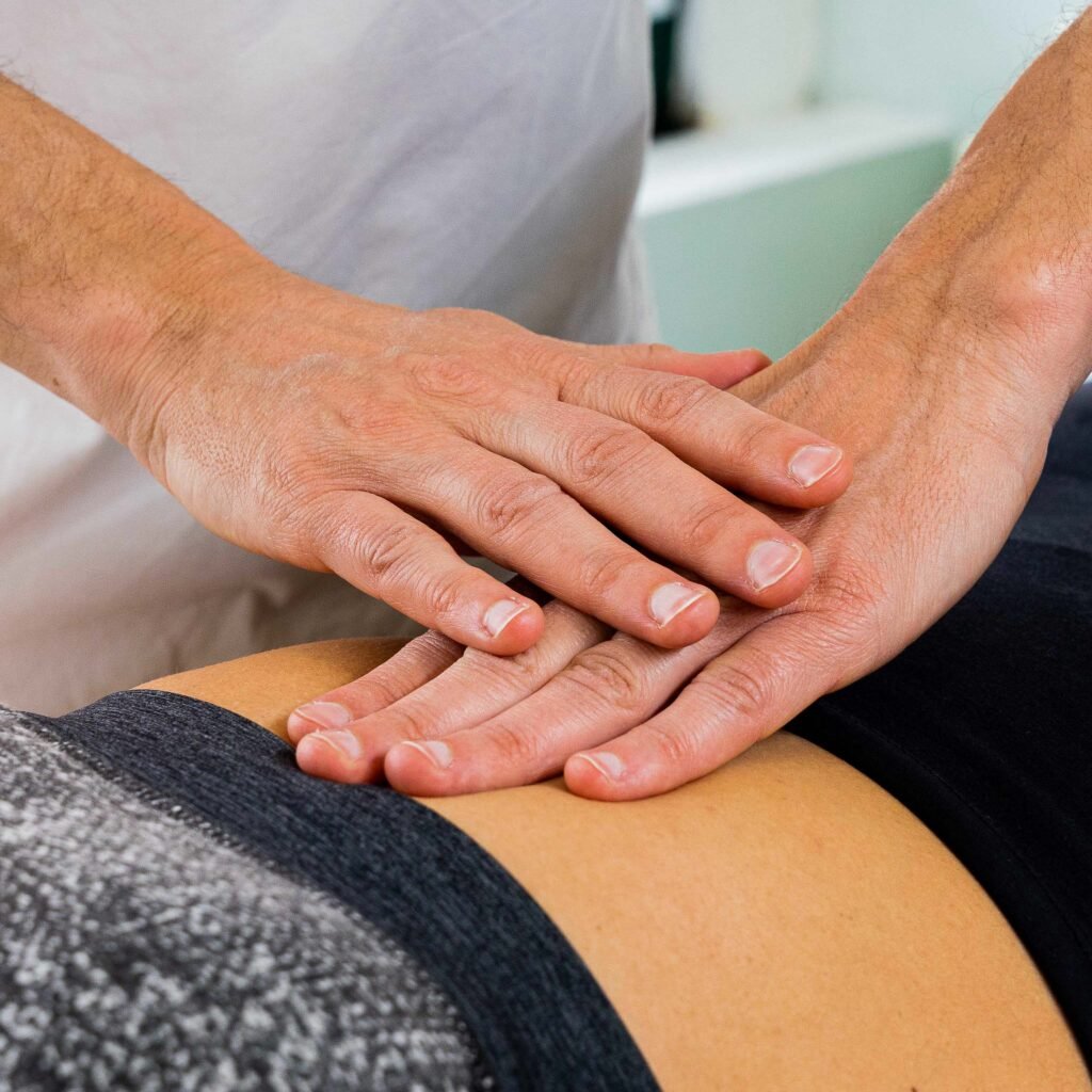 Mani dell'osteopata sulla zona lombare durante un trattamento a Carmagnola